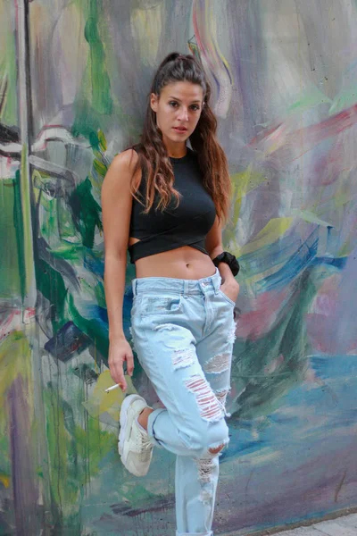 Trendi gyönyörű hosszú hajú fiatal modell pózol a graffiti vissza — Stock Fotó