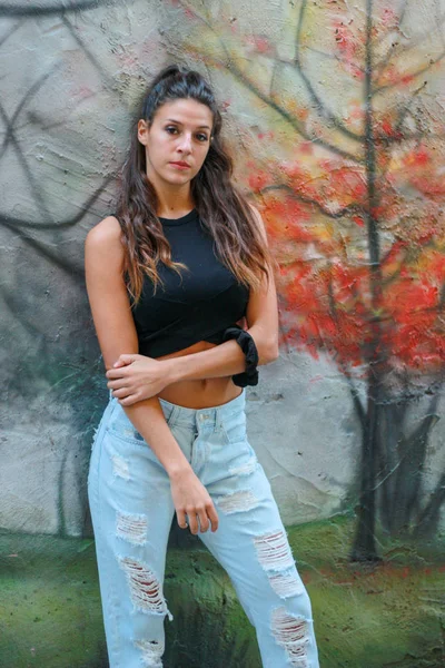 Trendy mooie langharige jonge model poseren op graffiti terug — Stockfoto