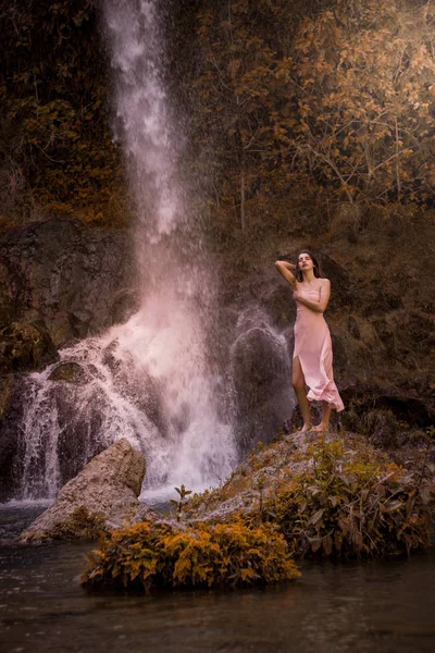 Attraktives Mädchen posiert auf dem Felsen inmitten des Märchenwaldes in lizenzfreie Stockfotos
