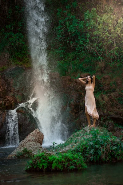 Sexy vrouw poseren op de rots onder groene tropische planten en worden — Stockfoto