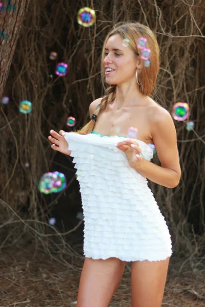 Счастливая красивая женщина, надувающая мыльные пузыри под открытым небом — стоковое фото