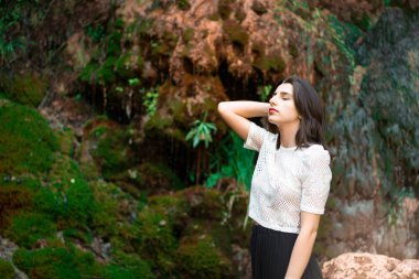 Güzel koyu saçlı kız yeşil bitkiler ile nehir poz. Olun