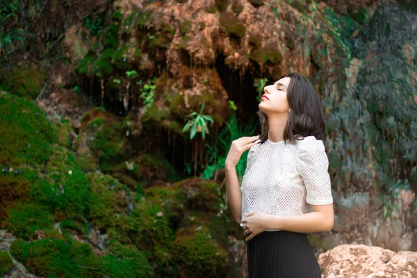 Hermosa chica morena posando en el río con plantas verdes. Sé —  Fotos de Stock