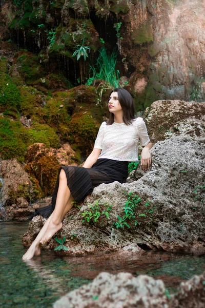 Hermosa chica morena posando en el río con plantas verdes. Sé —  Fotos de Stock