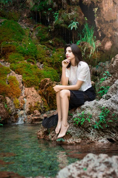 Güzel koyu saçlı kız yeşil bitkiler ile nehir poz. Olun