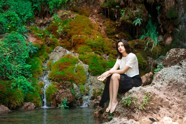 Hermosa chica morena posando en el río con plantas verdes. Sé —  Fotos de Stock