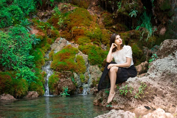 Hermosa chica morena posando en el río con plantas verdes. Sé —  Fotos de Stock