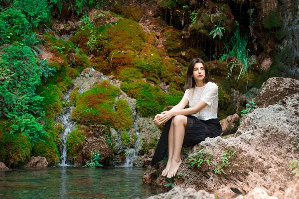 Hermosa chica morena posando en el río con plantas verdes. Sé —  Fotos de Stock