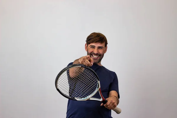 Portrait of handsome young man playing tennis holding a racket w