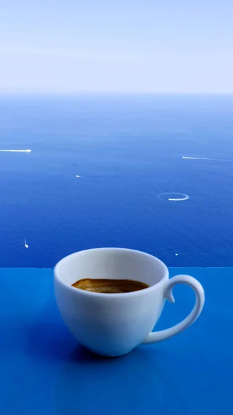 A cup of espresso coffee on the background of the sea and sky