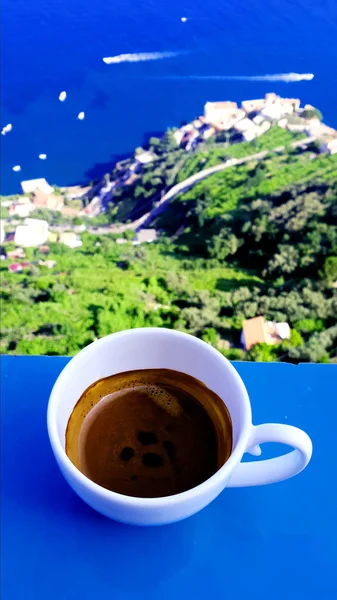A cup of espresso coffee on the background of the sea, mountains and sky