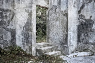 Terk edilmiş bir beton sinemada bir merdiven ile boş beton kapı