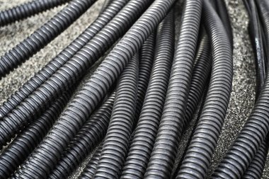 Bir avuç siyah Oluklu hortumlar yalan üzerine koyu gri kum