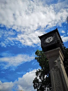 Bulutlu bir mavi gökyüzü ile bir parkta saat