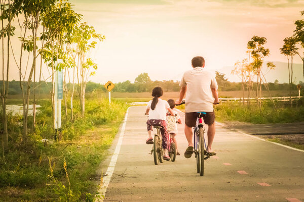 Famaly cycling on the street In the atmosphere there is sunlight.