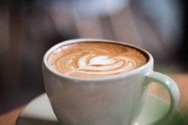 Kahve latte kalp şeklinde yığılmış üzerinde ahşap zemin, fincan kahve güzel Latte ile sanat.