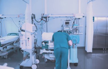 Erkek doktor yoğun bakım ünitesinde hasta yatağı yanında çalışma.