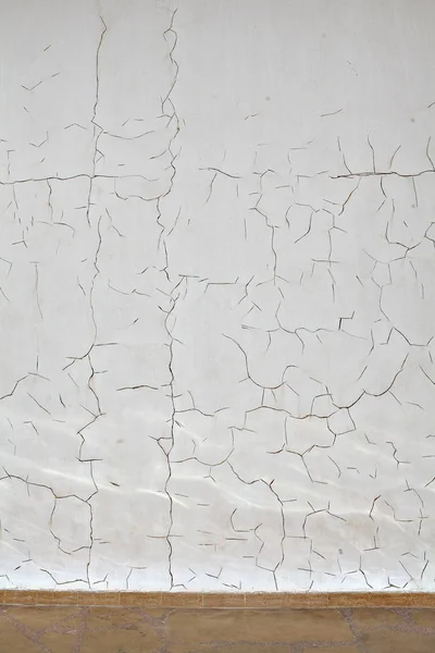 Pattern of cracks on the white plaster coated wall, textured background.