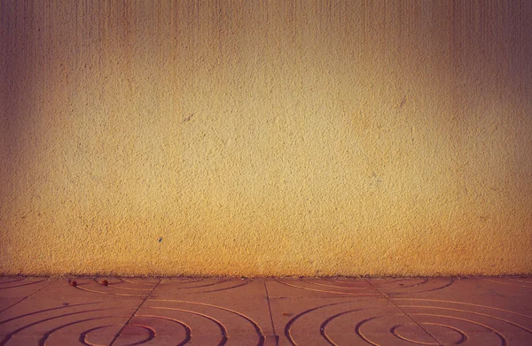 Meeting point of an exterior wall of house and concrete tile flooring, textured background.