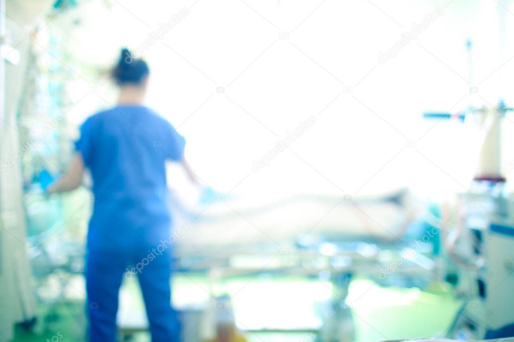 Female medical worker at the patient bed in the intensive care unit, unfocused background.