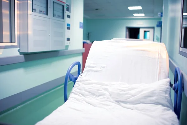 เตียงล้อที่ว่างเปล่าในห้องโถงโรงพยาบาลใกล้โต๊ะต้อนรับ — ภาพถ่ายสต็อก