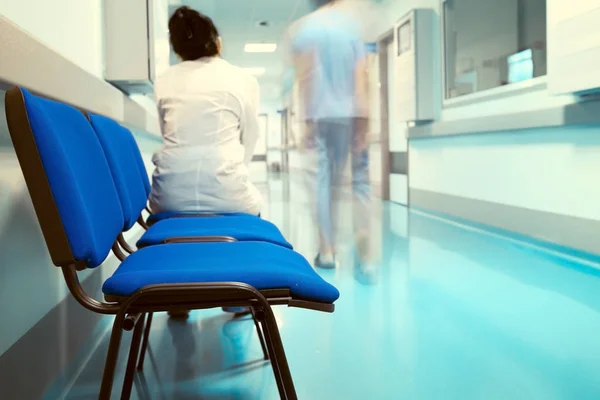 Ženský lékař sedí na židli v nemocničním koridoru. — Stock fotografie