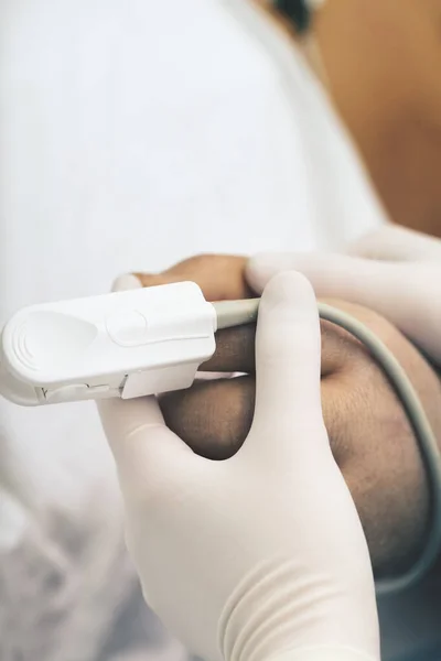 Verpleegster houdt de hand van de patiënt met een aangesloten pulsoximeter als een — Stockfoto