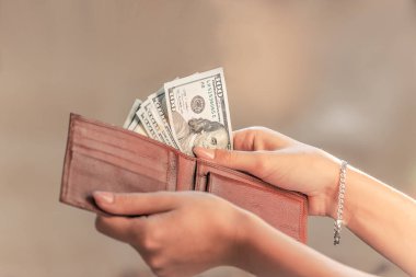 güzel kadın elleri bir kaç Amerikan Doları faturaları erkekler kahverengi deri çanta al, dengbags yarı-çanta, güzel ışık, renkli arka plan, gün ışığından yararlanma görülebilir