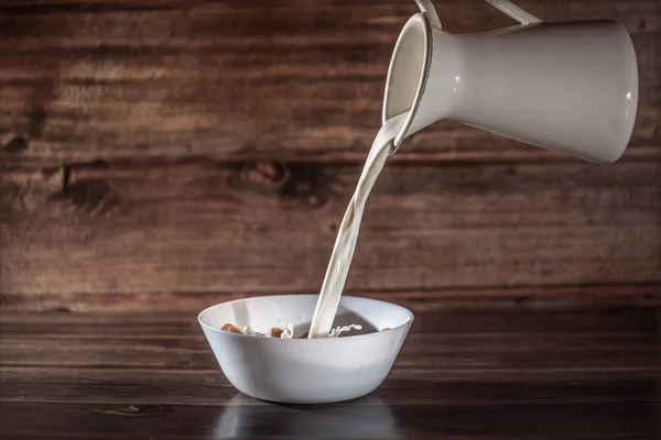 Latte Fuoriesce Brocca Bianca Proprio Piatto Bianco Con Cereali Colazione — Foto Stock