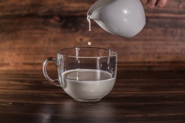 fotoğraf bir dizi, ahşap bir arka plan şeffaf bir fincan içine dökülen süt