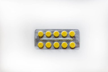 beyaz zemin üzerine sarı haplar islotaed paketi