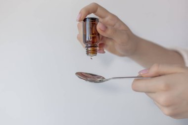 Beyaz arka plan üzerinde tutarak Damlalık ve kaşık kaşık, damla