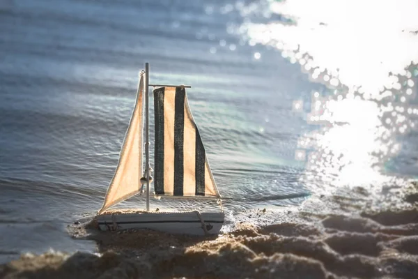 boat model toy ship near the sea on the beach on the sand lonely toy ready to big adventure  yacht for children sunny day