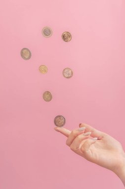 bir el, parmak, şans kavramı, pembe bir arka plan üzerinde bir para sikke düşmek