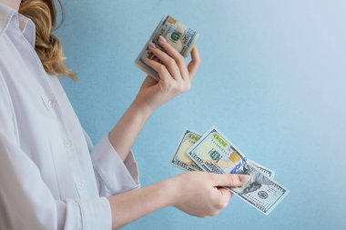 bir kız profilinde standları ve elleri faturaları ödemek, bir sürü para onun elinde, açık renkli mavi için onun elinde dolar tutar