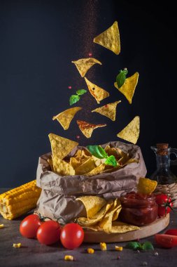 Nachos bir kağıt çanta içine düşmek, kırmızı biber Scatter Down, Yeşil fesleğen Mısır cips, domates ve baharatlı salsa sosu yanında uçar