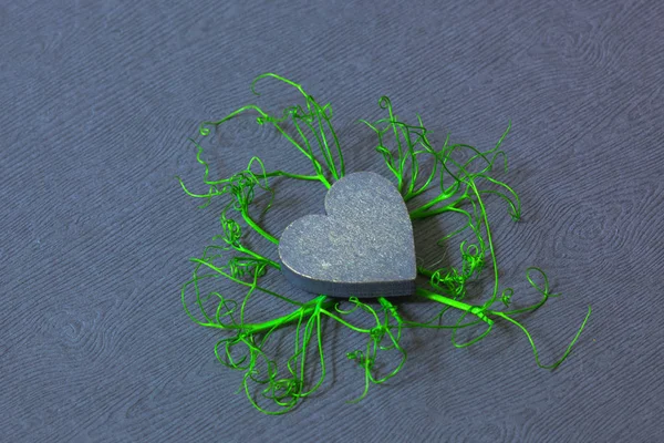 gray wooden heart with sprouts around, plants sprouted through the heart, the roots of a heart, to love and protect nature is an eco-friendly concept,