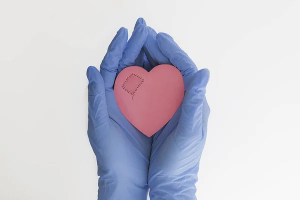 patch on the heart medicine, blue gloves, female hands, doctors save lives, concern for the health of the patient, pink heart, white background