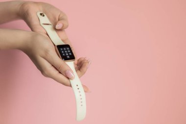 Saint-Petersburg, Rusya - 06.03.2019: Apple Watch altın kasa beyaz kum spor bandı kadın elinde, pembe arka planda izole, elektronik saatpin kodu n ekran 