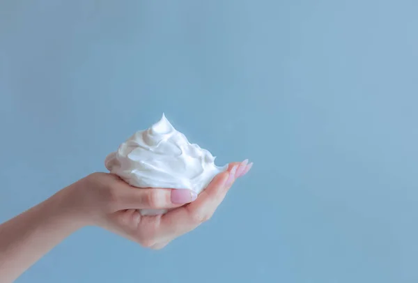 white bubbled foam in hands, hair foam, foam for man, white textured, hand full of soap isolated on blue background