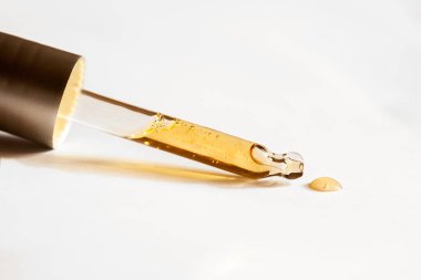  Beyaz arka plan üzerinde sarı yağ yakın çekim damlaları ile Pipet, seçici odak