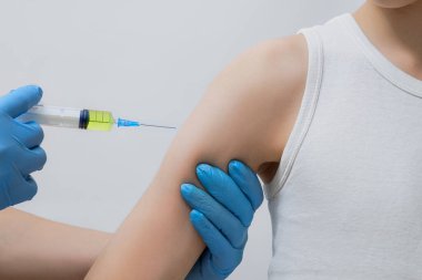Bir doktor omzuna enjekte eder, aşıyı yönetir, antiviral ilaçlar, bağışıklık aşısı, mavi eldivenli eller bir şırınga ile ilaç tutar.