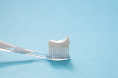 Mavi arka planda diş macunu olan beyaz diş fırçası, diş bakımı konsepti ve günlük ağız temizliği.