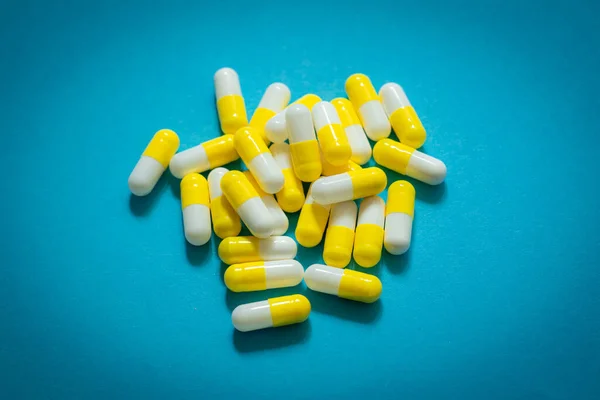 Lot of pills capsules on blue background.  Antibiotics drug resistance. Antimicrobial capsule pills. Pharmaceutical industry.