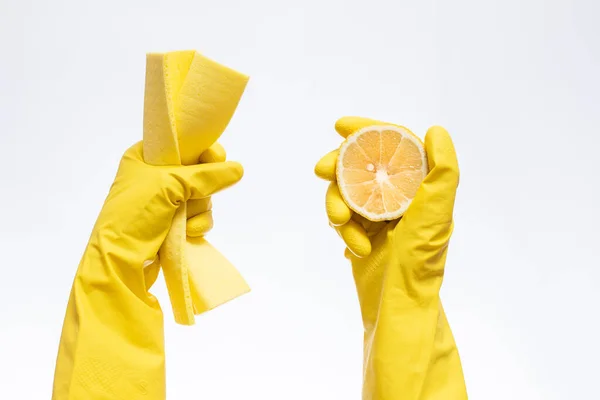 hands in yellow rubber gloves for cleaning hold a rag and lemon on a white background, natural cleaning products for home and kitchen, professional cleaning