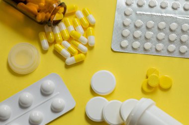 Tabletlerin yerleşimi, kapsüller, sarı arka planda anlık ilaçlar, eczane konsepti, çeşitli ağrı kesiciler, ağrı kesiciler.