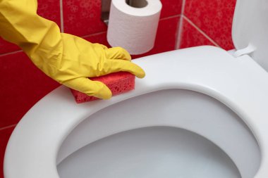 Klozet kapağını süngerle yıka, sarı eldivenli bir el tuvaleti yıka, profesyonel ev temizliği yap.