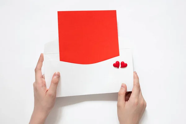 love letter in hand; red blank sheet; blank for design; place for text; red hearts on an envelope