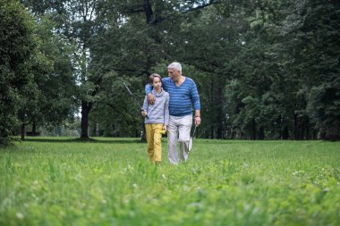 Oğlan ve büyükbaba parkta yürüyorlar, badminton raketleri ve elinde bir mekik horozu, emekli olurken aktif bir yaşam tarzı, torunla oynuyorlar.