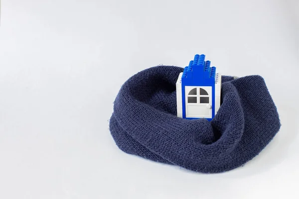 model of a house from blocks in a warm knitted scarf, the concept of a warm house, construction, insulation, heating in the winter season,